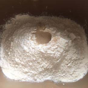 1:把所有主材料放入面包桶中，先液体，然后分别在两个角落放糖和盐，再高粉，中间挖个洞放入酵母，开启揉面模式