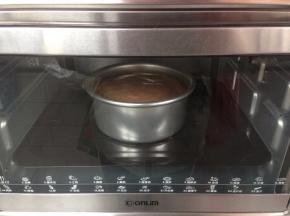 拌好的蛋糕糊从20CM左右的高度倒入到6寸的阳极活底蛋糕模里，再在桌面上震出气泡。放进已经提前预热好上火135度，下火150度的东菱K30A烤箱下层，烘烤63分钟左