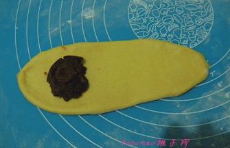将松弛好的小面团，擀成牛舌状，一端放上红豆馅；
