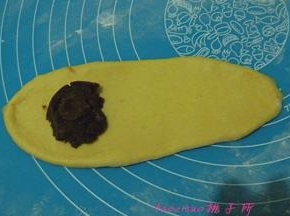将松弛好的小面团，擀成牛舌状，一端放上红豆馅；