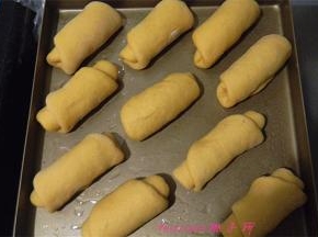 放好红豆馅，提起一端卷起，做好的面包胚放在烤盘里，包上保鲜膜二次醒发30~40分钟；