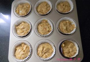 将拌好的蛋糕糊盛入蛋糕纸模里，至八分满，将蛋糕纸杯放入烤盘里；