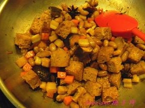 再放入烤麸、香菇和煮熟的花生翻炒，再加入红烧酱油翻炒；