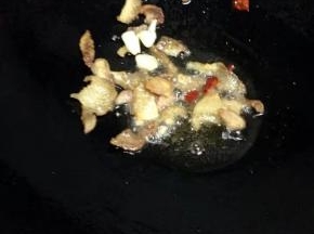 锅里倒入油，把猪肉加入翻炒变色，加入蒜和辣椒