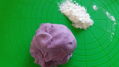 揉面结束后，取出面团，紫薯泥面团比白色面团稀点，准备点手粉进行下面的操作