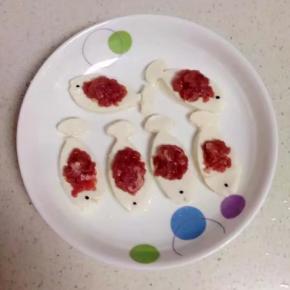 把肉末放在鱼型豆腐中间。用黑米做鱼眼睛。