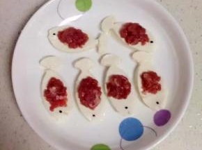 把肉末放在鱼型豆腐中间。用黑米做鱼眼睛。