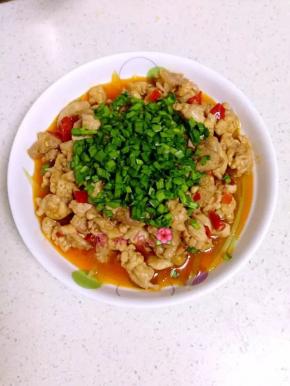 爆炒好的鸡肉盛出倒在铺了锅笋的盘子里，再把切好的韭菜撒上。