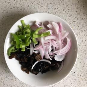 沥干水的木耳放入碗内，倒入切好的洋葱，青椒