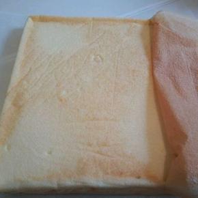  烤好，从烤箱取出蛋糕，垂直震一下，趁热把油纸撕开，反面朝上。
撕掉后马上翻面，正面朝上，不然水蒸气加油纸一焖，正面皮会沾掉