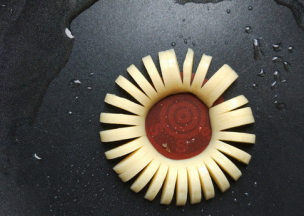 将切好的香肠摆到不粘锅中间，开小火加热，边将香肠环成圆形。要一点点弯曲香肠，最终环成圆形，不要直接头尾相接，很容易一下子掰断。香肠稍加热会比较柔软，比较好弯。