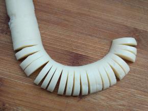 将香肠切去两边圆头，如图切开，一边相连不切断。因为香肠很软，拖刀的话会扯断，最好一手捏着香肠，一手用小刀切