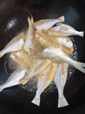 锅烧热倒入适量的油烧至七成热，放入吸干水分的小黄鱼，中小火慢慢的煎！

