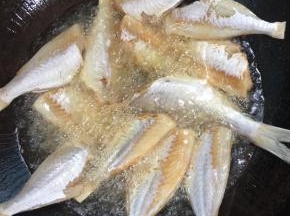 锅烧热倒入适量的油烧至七成热，放入吸干水分的小黄鱼，中小火慢慢的煎！

