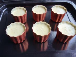 将模具送入烤箱180度不预热烤3分钟，取出将模具内壁刷上黄油，倒放在烤网上，沥干多余的黄油。将面糊倒入处理好的模具中，离杯口约0.5厘米。