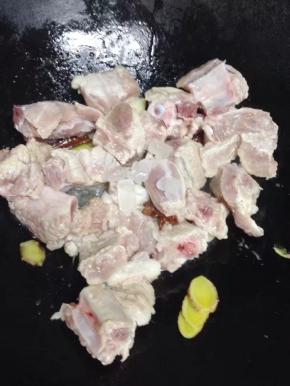 加入排骨、冰糖放入锅中炒至棕红色，排骨上色。