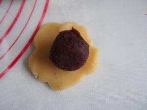 将面团压扁，包上蛋黄豆沙馅