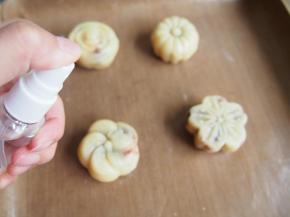 将压好的月饼放在烤盘上，烤箱预热到160度，喷上一层清水，烘烤5分钟定型