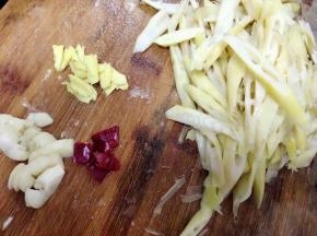 苦笋焯水后切片备用。大蒜略拍，姜切小片。