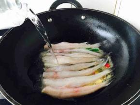 放入龙头鱼，中火煎1分钟，倒入清水1200ml。