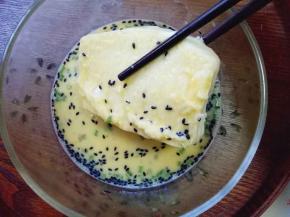 馒头片用筷子夹着，再鸡蛋液的容器里裹上蛋液，裹均匀。