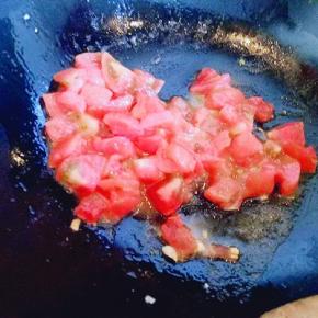 锅中加入少量油，倒入切好的番茄煸炒，炒至番茄炒软。