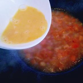 锅中的番茄烧开后，洒入蛋液(鸡蛋用画圈的手势倒入锅中，切记不要一下子把鸡蛋液倒入锅中。)拿着碗围绕锅的一圈慢慢倒入。