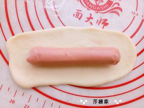 取一份面团擀开，放一个烤肠。卷好，摆在阳晨金色烤盘里。进行二次发酵。（有船型纸托的可以放进纸托里烤出来的形状会更好看）