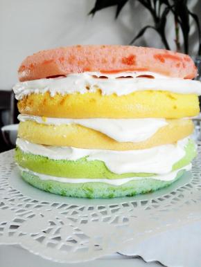 裱花台上放一张蛋糕托，取蓝色的蛋糕胚放在蛋糕托上，抹一层奶油霜，再取绿色的蛋糕胚，抹一层奶油霜，再取原味的蛋糕胚，抹一层奶油霜，再取黄色的蛋糕胚，抹一层奶油霜，再取红色的蛋糕胚，抹一层奶油霜，从上到下颜色分别是：红，黄，原，绿，蓝