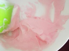 取少许奶油霜，放入碗中，滴入一滴红色素，搅拌均匀，红色奶油霜完成