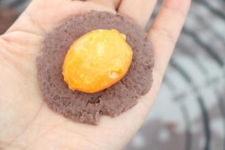 红豆沙球在手掌按扁，包入咸蛋黄