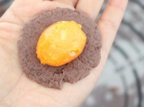 红豆沙球在手掌按扁，包入咸蛋黄