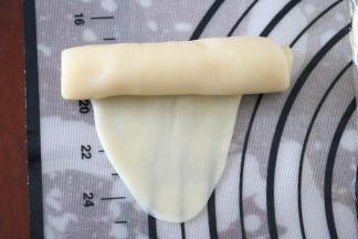 将松弛好的面团用手掌按扁，再用擀面杖擀成椭圆形，由上至下卷起