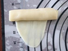 将松弛好的面团用手掌按扁，再用擀面杖擀成椭圆形，由上至下卷起
