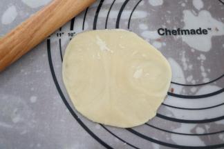 对夹方向朝上，用手掌按扁，再用擀面杖把面皮擀成中间厚，边缘薄的饼皮