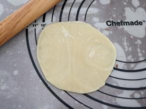 对夹方向朝上，用手掌按扁，再用擀面杖把面皮擀成中间厚，边缘薄的饼皮