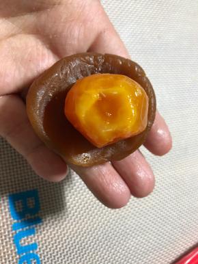 蛋黄凉透后再包，我的蛋黄是中号的，用的50克月饼模具，50克模具应该用小号蛋黄更合适，或者中号蛋黄，用75克的模具也可以。用掌心压扁馅球，放入蛋黄