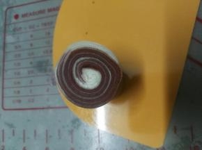 松弛好的面团从中间平均切成两个，下刀要快，这样切面才平整；螺旋纹朝上用手压扁；再用擀面棍擀圆，中间厚四周薄；翻过面来放上红豆沙