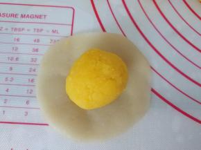 取一个原色饼皮，擀成圆形，包入奶黄馅