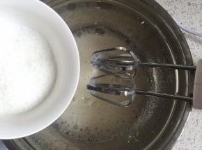 用电动打蛋器低速打发至蛋清呈粗泡，加入1/3的细砂糖，继续中速打发