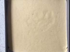 方盘垫上油纸，倒入蛋糕糊，在桌上轻磕几下震出大气泡