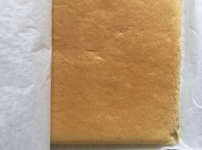 烤好的蛋糕取出，在桌上轻磕一下震出热气，顺着油纸提出蛋糕，稍微凉一下撕去油纸，然后再盖上油纸以免干燥，等待蛋糕放凉