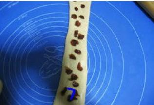 松驰好的面团按扁，擀成椭圆形，翻面卷起，松驰10分钟；
    将松驰完的面团压扁，擀长，放上适量桂圆干；