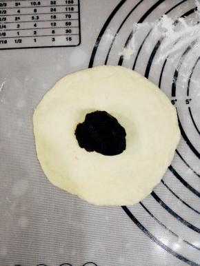 取一个面团，擀成一个圆形的面饼，放上10克红豆沙