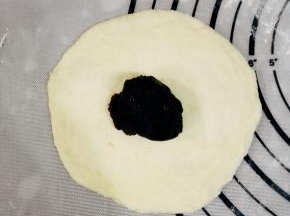 取一个面团，擀成一个圆形的面饼，放上10克红豆沙