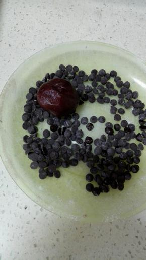 将剩下的巧克力豆放入小盘中，放入搓成圆形的面团，使其表面均匀的粘上巧克力豆