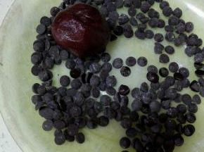 将剩下的巧克力豆放入小盘中，放入搓成圆形的面团，使其表面均匀的粘上巧克力豆