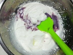 将蓝莓果酱液分三次倒入淡奶油盆中拌匀