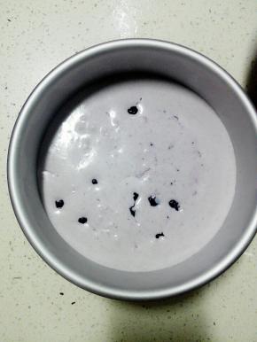 从冰箱取出模具，倒入一半的蓝莓慕斯液，放入适量蓝莓