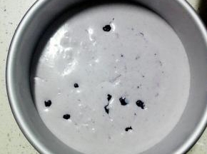 从冰箱取出模具，倒入一半的蓝莓慕斯液，放入适量蓝莓